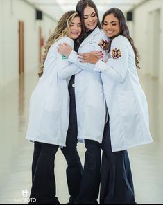 three women in white coats hugging each other