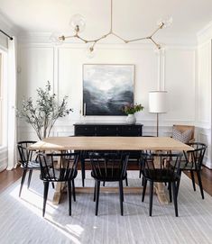 the dining room table is surrounded by black chairs and an art piece on the wall