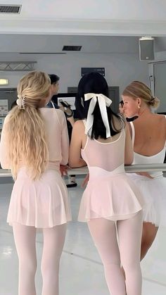 three ballerinas in pink tutus and white leotards looking at each other