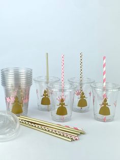 the cups are lined up with gold straws and pink paper straws on them