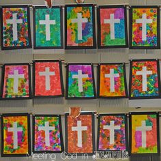 cross paintings are hung on the wall in front of a bulletin board that is decorated with colorful paper