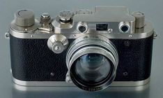 an old fashioned camera sitting on top of a white table with its lens pointed up