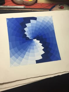 an art work with blue and white shapes on paper next to paintbrushes, watercolor