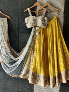 This yellow butti georgette lehenga with heavy gota and zari work border detailing is paired with a mirror bustier blouse.  The outfit is completed with an ivory sequin work net dupatta with scallop edging. Luxury Yellow Lehenga For Puja, Luxury Yellow Semi-stitched Lehenga, Luxury Yellow Blouse With Dupatta, Luxury Yellow Blouse Piece With Sheer Dupatta, Luxury Yellow Georgette Lehenga, Luxury Yellow Tops For Navratri, Luxury Yellow Blouse Piece With Dupatta, Yellow Lehenga For Diwali, Luxury Semi-stitched Yellow Choli