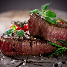 two steaks on a cutting board with herbs