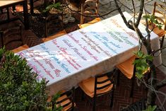 a table covered with a sign sitting on top of a wooden bench next to a tree