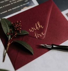 a red envelope with the word wish love written on it next to a pen and flower