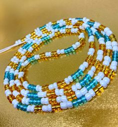 three strands of beaded necklaces with white and blue beads on a gold background