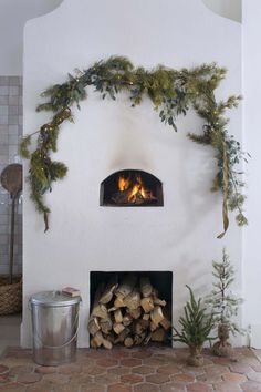 a fireplace with logs and greenery around it