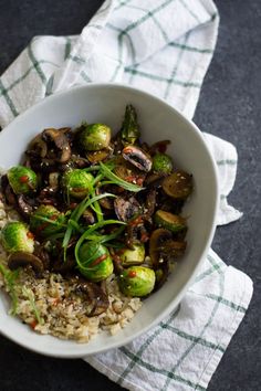 a white bowl filled with rice and veggies on top of a table next to a napkin