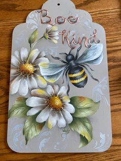 a bee is sitting on top of a flower with the words bee kind painted on it