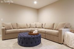 a living room with a couch, ottoman and coffee table in the middle of it