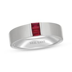 a white gold ring with a red stone in the center and an inscription on the side