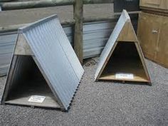 two metal boxes sitting next to each other on top of gravel covered ground near wooden posts