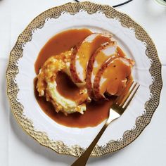 a plate topped with mashed potatoes covered in gravy next to a fork