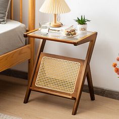 a small wooden table with a lamp on it next to a bed in a room