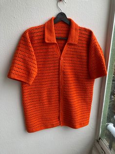 an orange sweater hanging on a white wall