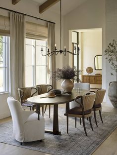 a dining room table with chairs and a chandelier hanging from it's ceiling