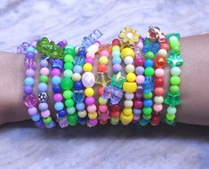 a woman's arm with several bracelets on top of it, including beads and bows