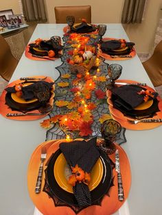 the table is set with black and orange place settings