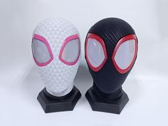 two masks with red and white eyes are sitting on black bases against a white background