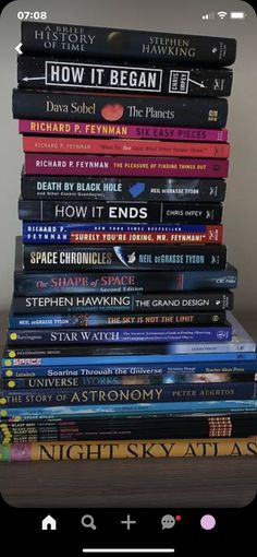 a stack of books sitting on top of a wooden table next to a phone screen