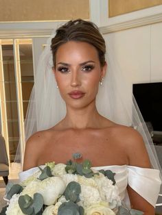 a woman in a wedding dress holding a bridal bouquet and looking at the camera