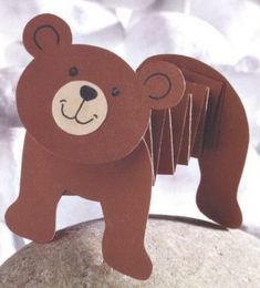 a brown bear standing on top of a rock next to a pile of paper clips