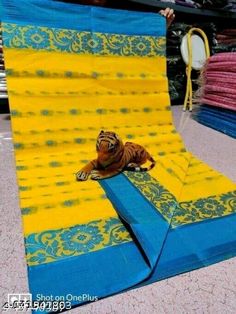 a stuffed animal laying on top of a blue and yellow blanket in the middle of a store