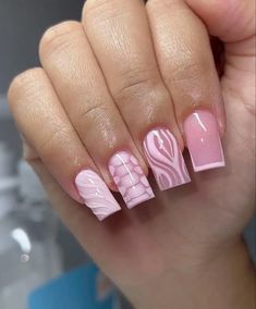 a hand with pink and white nail designs on it