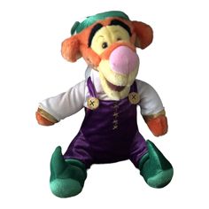 a stuffed animal that is wearing overalls and a green hat with an orange nose