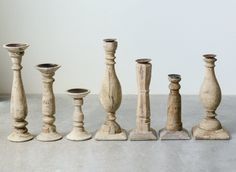 several wooden candlesticks are lined up in a row on the floor next to each other