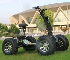 an off - road vehicle is parked in the grass near a building with large windows