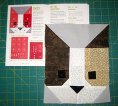 an animal made out of paper sitting on top of a cutting mat next to scissors