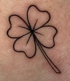 a four leaf clover tattoo on the back of a woman's arm with black ink