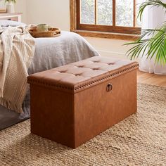 a bed room with a large window and a wooden trunk on the floor next to it