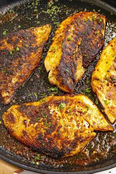 three pieces of chicken cooking in a skillet