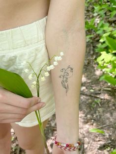 a woman with a flower tattoo on her arm is holding a plant in her hand