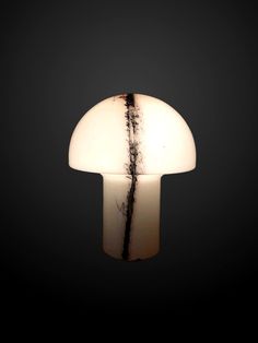 a mushroom shaped light with black and white stripes on it's side, against a dark background