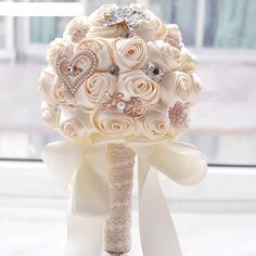 a bridal bouquet with white roses and diamond brooches is shown in front of a window