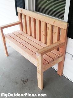 a wooden bench sitting in front of a window on the side of a door way