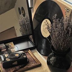 a record player sitting on top of a table next to a vase filled with lavender