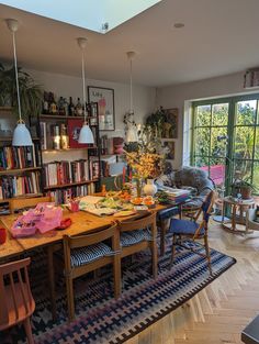 a dining room table and chairs in front of a large book shelf filled with books