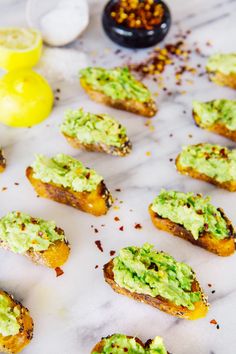 several pieces of bread with guacamole on them sitting on a white table