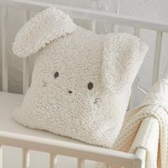 a stuffed animal pillow sitting on top of a white crib next to a blanket