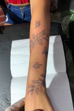 a woman's arm with butterflies on it and her hand resting on the table