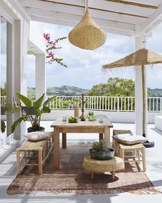 an outdoor dining area with wicker furniture and large plants on the table in front of it