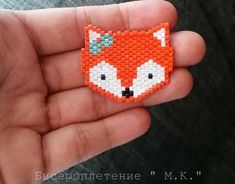 a hand holding a small beaded fox brooch