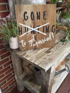 a wooden sign that says gone hunting to get married on top of an old table