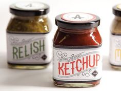 three jars of relish sitting on top of a white table next to each other